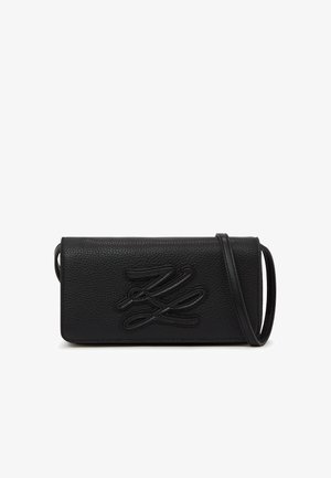 Fekete, texturált bőr keresztpántos táska dombornyomott, stilizált monogramokkal és vékony vállpánttal, fehér háttér előtt kiállítva.