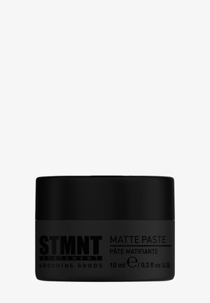 Contenant de pâte noir mat avec une finition lisse, présentant un grand texte blanc pour les détails de la marque et du produit. Contient 10 ml de produit.
