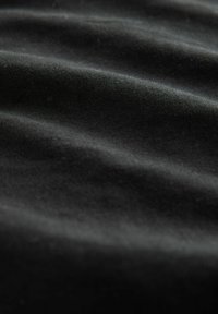 Zwarte stof met een zachte textuur, voorzien van subtiele golven en zachte plooien, die een consistente kleur en lichtgewicht materiaal laat zien.
