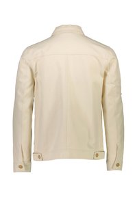 Krämfärgad jacka med krage, bakstycke, osynlig söm och knäppning vid ärmsluten. Har ett slätt, strukturerat tyg och sidoflikar.