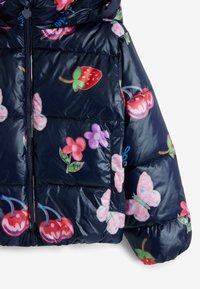 Vadderad marinblå jacka med en blank yta, prydd med färgglada frukt- och blommönster i röd, rosa, grön och blå. Dragkedja som stängning.