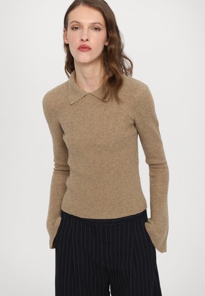 Beige, ribbet strikkegenser med rund hals, lange ermer og strukturert stoff, kombinert med pinstripede bukser.
