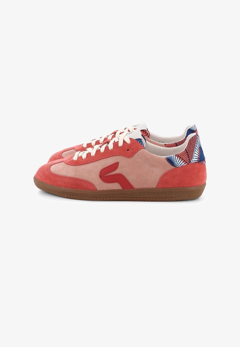 Paire de baskets basses en daim rose et rouge avec des lacets blancs, des semelles brunes et un tissu à motif bleu-rouge autour du talon.