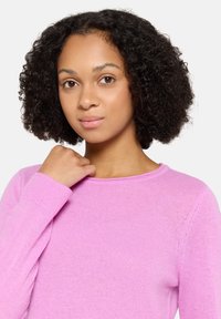 Pull rose à manches longues et encolure ronde, confectionné dans un tissu tricoté doux et léger. Présente une texture lisse et une coupe ajustée.