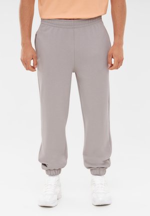 Grå sweatpants med elastisk talje og manchetter ved anklerne. Lavet af blødt materiale, med sidelommer og en afslappet pasform.