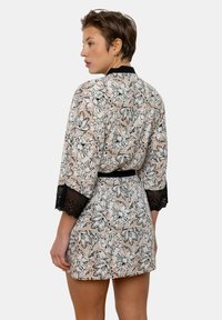 Kimono floral en rose avec contour noir ; présente des manches en dentelle et une ceinture assortie. Tissu doux avec une coupe ample et une longueur au genou.