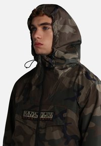 Giacca camouflage realizzata in tessuto impermeabile, con chiusura a zip, cappuccio regolabile e patch con logo sul petto.