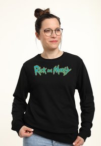 Sudadera negra con el logo de "Rick y Morty" en verde y azul, con cuello redondo y mangas largas. Tejido suave y corte holgado.