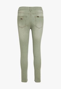 Úzké džíny ze světlého zeleného denimu se středním pasem. Mají dvě zadní kapsy a malou cedulku na pásku pasu. Švy jsou dokončené hladce.