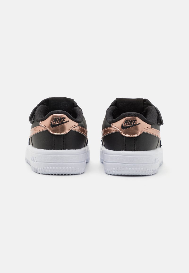 Baskets en cuir noir avec accents rose doré, collier rembourré et semelle en caoutchouc blanc. Présente le logo Nike au niveau du talon en noir.