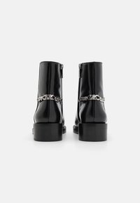 Black patent ankle boots featuring a silver chain accent and a chunky heel. The back includes a zipper closure for easy wear.