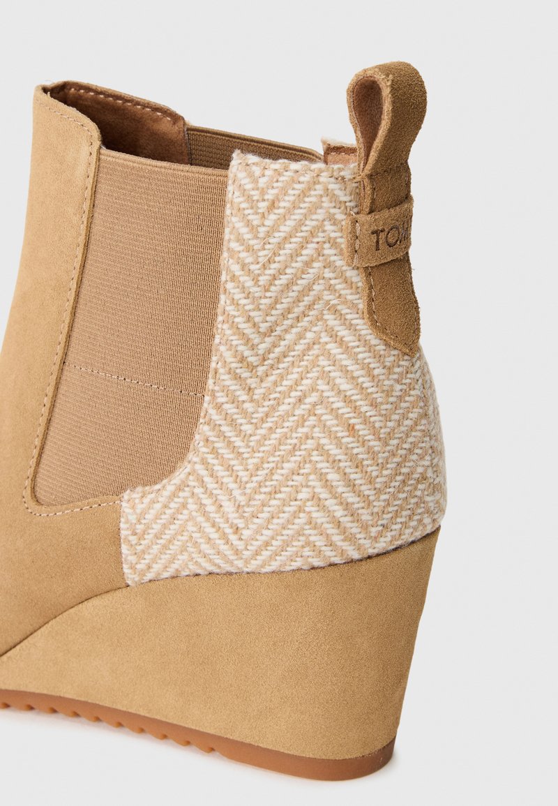 Bottines en suedine tan avec un panneau en tissu chevrons, des côtés élastiques et un talon en wedges marron. Comprend une languette à l'arrière.