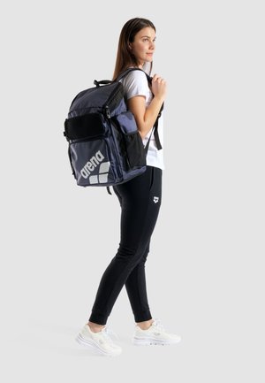 Zaino blu navy con dettagli neri. Caratterizzato da più scomparti, una tasca in rete e un logo bianco ben visibile. Forma grande e rettangolare.