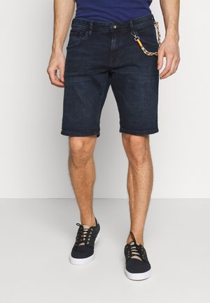 Shorts en denim bleu foncé avec une coupe standard, ourlets retroussés, cinq poches et une chaîne décorative attachée à la poche avant.