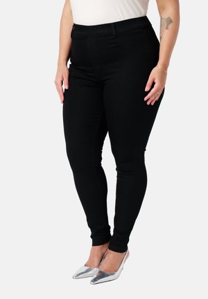 Zwarte skinny jeans van stretchdenim met een hoge tailleband en zijzakken, aangevuld met zilveren puntige hakken.