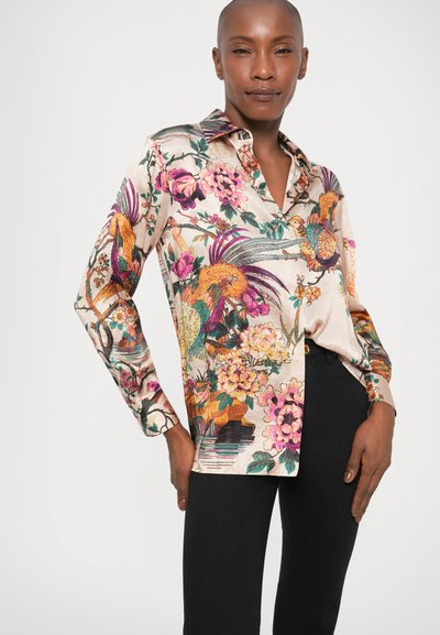 Camisa de manga larga en material similar a la seda, con vibrantes patrones florales y de aves en rosa, verde y naranja sobre un fondo claro.