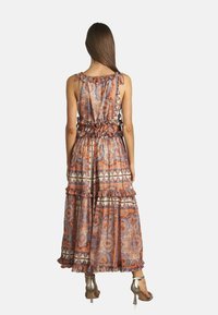 Abito lungo in tessuto leggero con motivi paisley e geometrici. Presenta strati arricciati, spalline regolabili e vita arricciata.