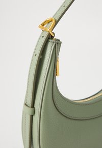 Green leather handbag with a structured design, featuring a gold hardware accent and contrasting stitching along the edges.