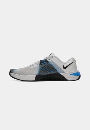 White, black, and blue Nike athletic shoe with mesh upper, black swoosh logo, and textured sole, shown in side profile on white background.