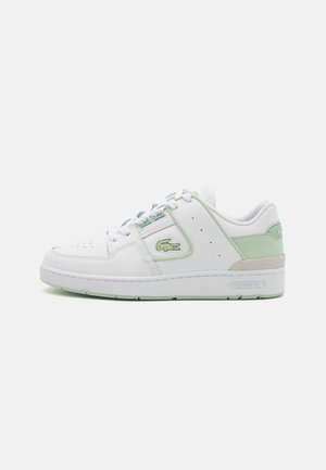 Sneaker in pelle bianca con dettagli verde menta, punta rotonda, design perforato, chiusura con lacci e suola testurizzata. Logo Lacoste sul lato.