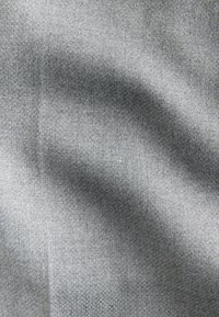 Close-up of light gray fabric with visible weave texture and soft folds creating shadowed areas.