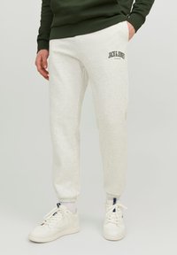 Light gray jogger pants with cuffed ankles and an embroidered "JACK & JONES" logo. Made from soft fabric, paired with white sneakers.