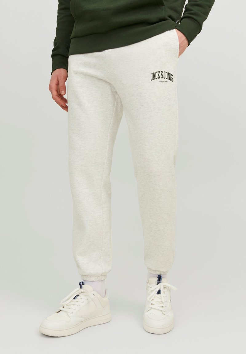 Light gray jogger pants with cuffed ankles and an embroidered "JACK & JONES" logo. Made from soft fabric, paired with white sneakers.
