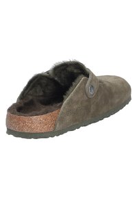 Zapatilla de ante verde oliva con suela de corcho, forro suave y cierre de botón lateral. La suela exterior tiene un agarre texturizado para mayor tracción.