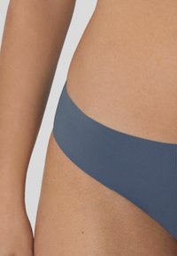 Modré bezšvové bikiny s hladkou texturou a širokým pasem, se minimalistickým designem a bez viditelných švů.