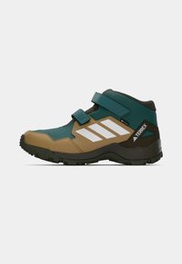 Green and brown mid-cut hiking shoe with Velcro strap, textured upper, white stripes, and rubber sole featuring traction patterns.