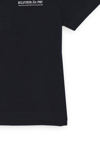 Polo navy in cotone, con colletto classico, maniche corte e logo ricamato bianco sulla parte superiore sinistra.