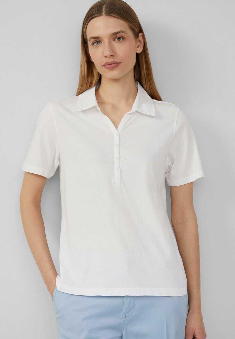 Weißes Polohemd mit kurzen Ärmeln, Kragen und einer fünfknöpfigen Knopfleiste, aus weichem Baumwollstoff gefertigt, mit lockerem Schnitt und glatter Textur.