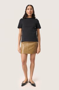 Tricou din bumbac negru, cu mâneci scurte, asociat cu o fustă mini din piele maro, pantofi slingback negri, texturi netede și un design ajustat.
