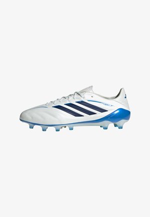 Witte en blauwe Adidas voetbalschoen met donkerblauwe strepen en een noppenzool, ontworpen voor spelen op harde ondergrond.