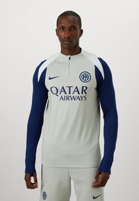 Nike team trainingshirt met een grijze body, marineblauwe mouwen, een kwart-rits sluiting en bedrukte logo's van Qatar Airways en het clubembleem.