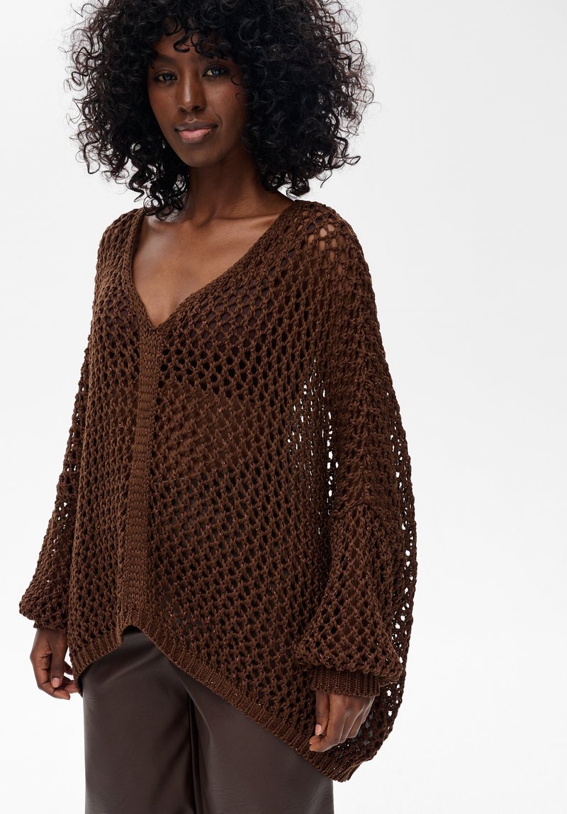 Brązowy sweter robiony na drutach o luźnym, otwartym kroju, z dekoltem w serek i długimi rękawami. Teksturalny splot dodaje wizualnego zainteresowania i głębi.