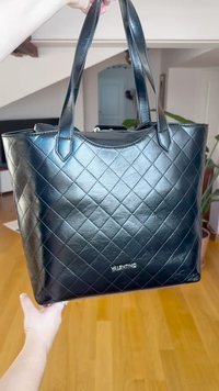 Juoda siuvinėta odinė rankinė su dviem tvirtais rankenomis, užtrauktuku ir subtiliu logotipu priekyje. Lygi tekstūra, stačiakampio formos.