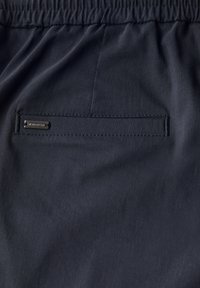 Marineblå shorts med elastisk talje og en baglomme med et lille metallisk logo og glat, letvægtsstof.