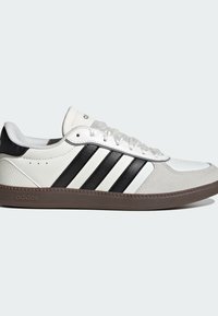 White sneaker with black leather stripes, textured grey suede toe, rubber brown sole, and lace-up design. Features adidas branding on tongue.