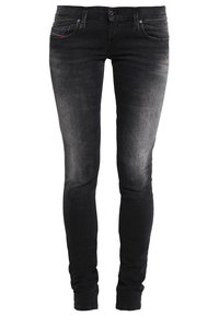 Skinny jeans in faded black denim. Features five pockets, belt loops, a zipper fly, and a small red accent near the front pocket.