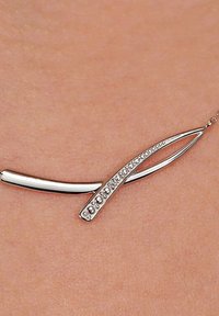 Silberne Anhängerkette mit zwei geschwungenen Formen; eine glatt und glänzend, die andere mit kleinen klaren Kristallen verziert.