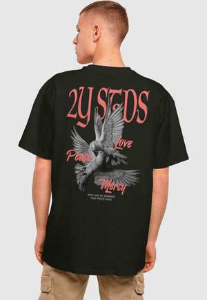Schwarzes T-Shirt mit einer großen Grafik von zwei fliegenden Tauben. Der Text umfasst "2Y STDS", "Frieden", "Liebe" und "Barmherzigkeit" in Rot.
