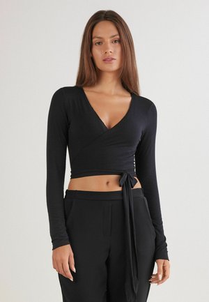 Black long-sleeve wrap top made of soft fabric with a deep V-neck and side tie, featured with a fitted design and smooth texture.