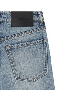 Vaqueros de mezclilla en un lavado azul claro con un diseño clásico de cinco bolsillos. Parche de cuero negro con la marca en la cintura. Detalles de costuras en contraste.