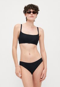 Svart bikini-set med en topp med fyrkantig halsringning, tunna axelremmar och hög midja, texturerat mönster och slät yta.