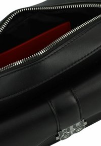 Borsa a mano in pelle nera con zip argentata e fodera interna rossa. Include una tasca piatta all'interno e una superficie liscia.