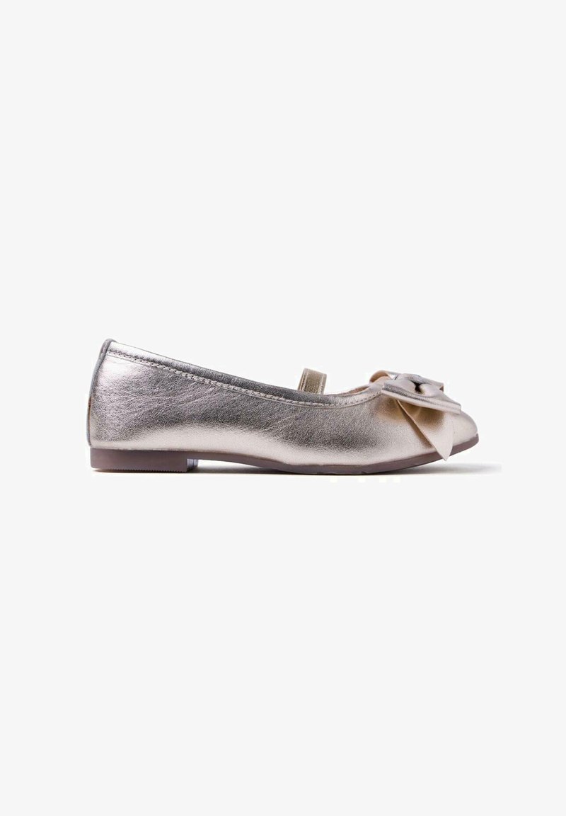 Zapato plano plateado metálico con punta redonda, correa lateral y un gran lazo decorativo en la parte delantera, mostrado en perfil lateral sobre un fondo blanco.