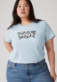 Ανοιχτό μπλε βαμβακερό T-shirt με κοντά μανίκια, με γραφικό του λογότυπου Levi's με θέμα τα λουλούδια σε μαύρο και άσπρο στο μπροστινό μέρος.