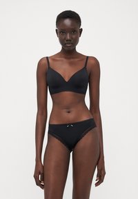 Ensemble de lingerie noire comprenant un soutien-gorge sans coutures avec des bretelles ajustables et un slip assorti avec des dentelles et un nœud décoratif à l'avant.