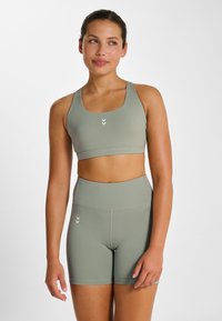 Sport-bh och höga shorts i dämpad grön färg. Elastiskt, sömlöst tyg med subtil logotypdetalj och rena linjer.